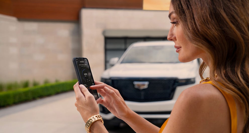 lady checking her mobile with a Cadillac vehicle background | DeVoe Cadillac in Naples FL