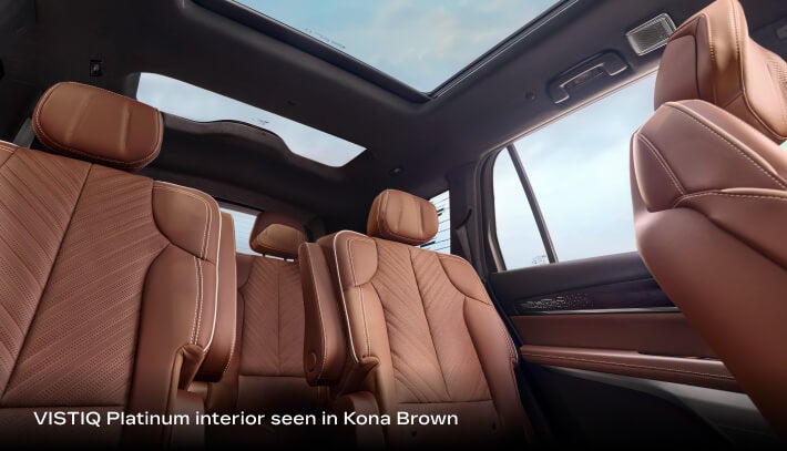 2027 Cadillac VISTIQ Platinum with Kona Brown second and third-row seating beneath a panoramic glass roof.