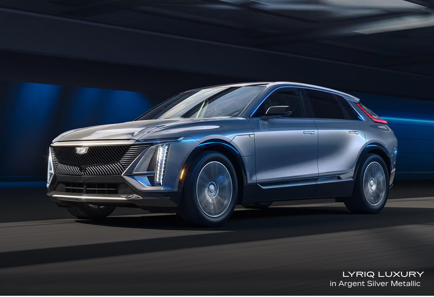 Front-three-quarter view of a Cadillac LYRIQ Luxury in Argent Silver Metallic driving through a tunnel.
