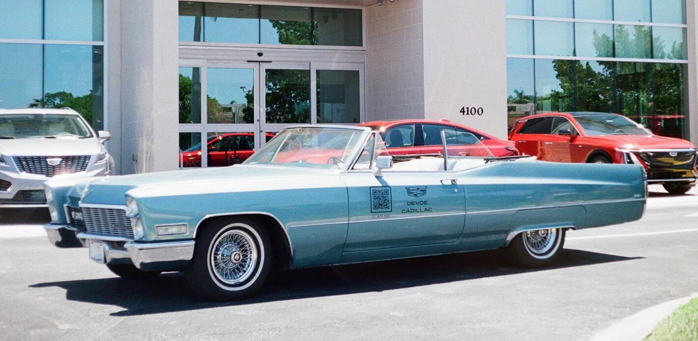 A baby blue classic Cadillac convertible parked outside Devoe Cadillac.